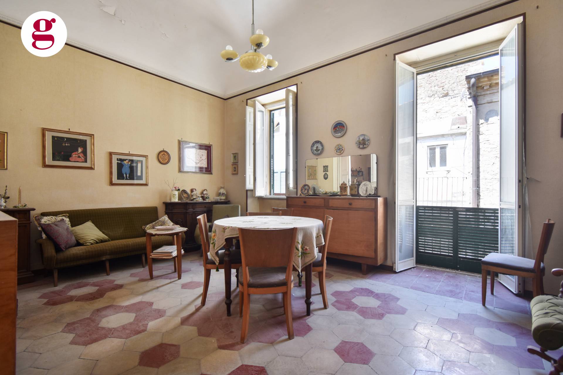 Old salon with ochre walls, hexagonal tiled floor and balcony doors