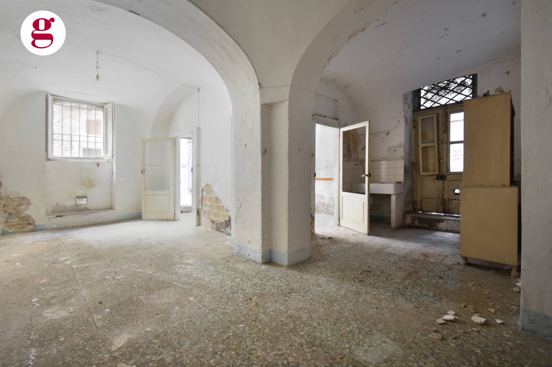 Empty vaulted ground floor room with peeling plaster and terrazzo floor
